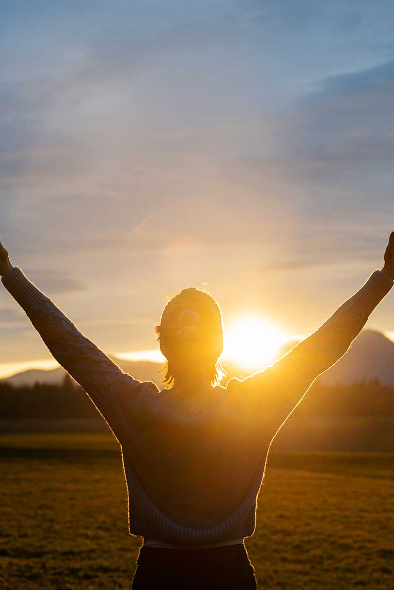 Woman with arms open viewing a sunset